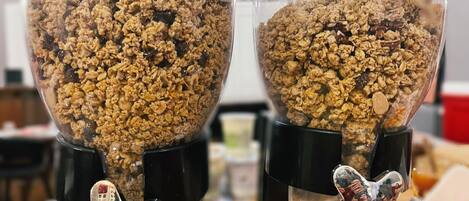 Two clear glass containers filled with granola, each with a unique metal figure at the bottom.