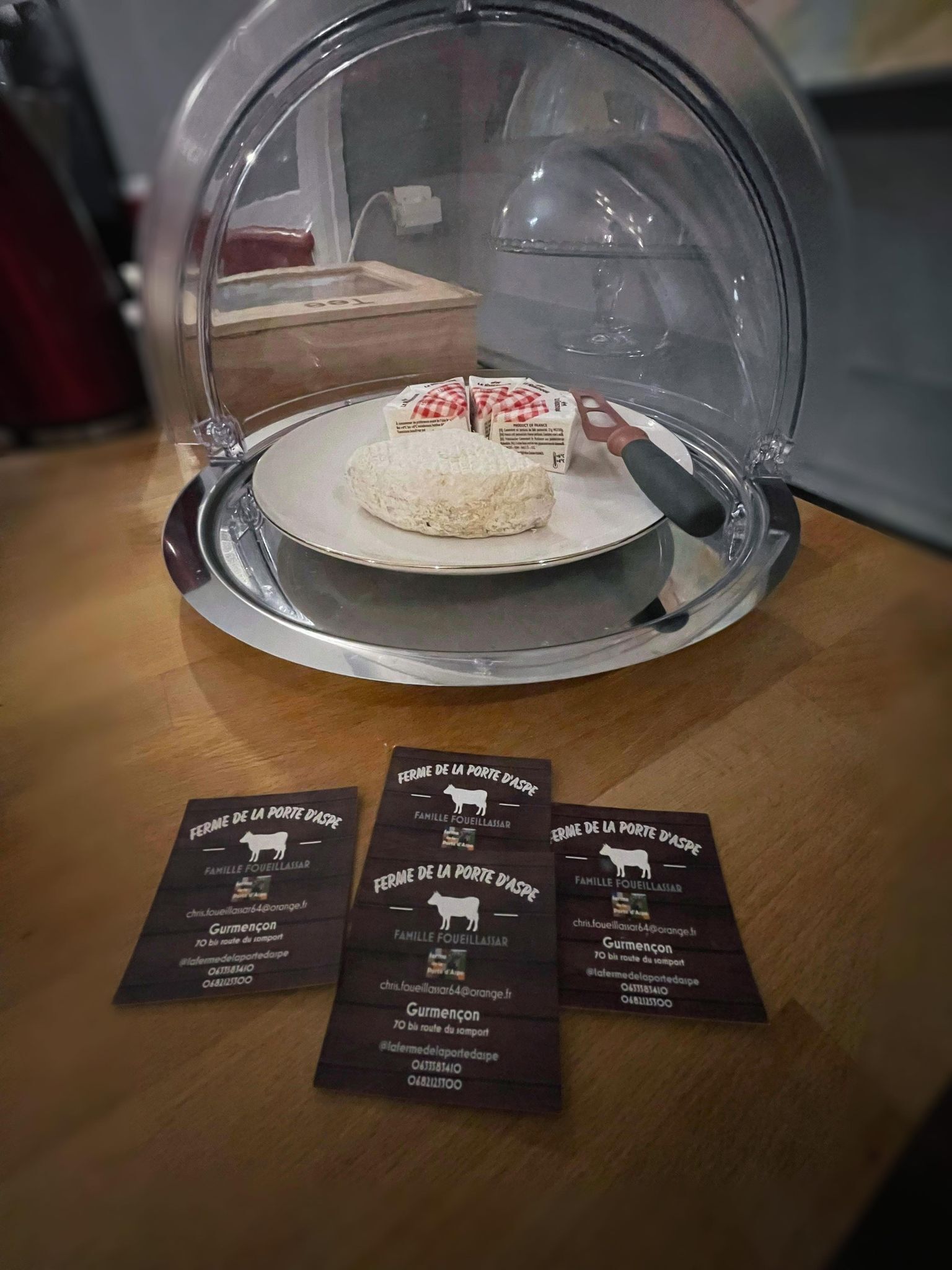 A food display with a glass dome, a plate with pastries, and three business cards.