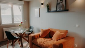 A modern living room with a round glass table, a sofa, and a chair. - Le Central Hôtel Bar (Oloron-Sainte-Marie)