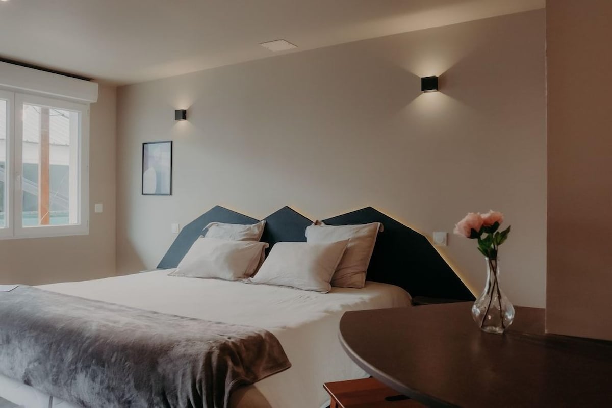 A modern bedroom with a bed, bedside table, and a vase with flowers.