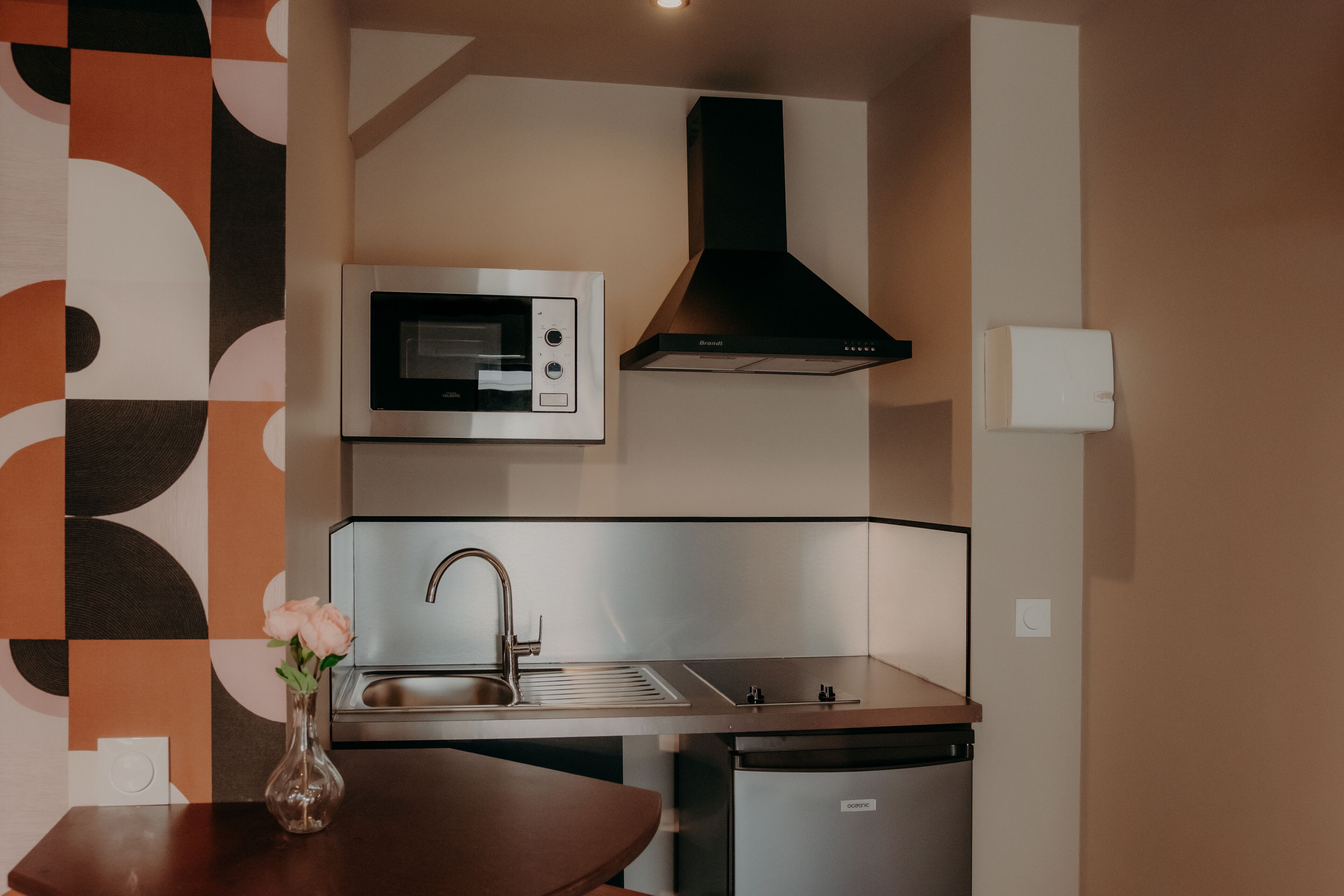 A modern kitchen with a built-in microwave, stainless steel sink, and a black range hood.