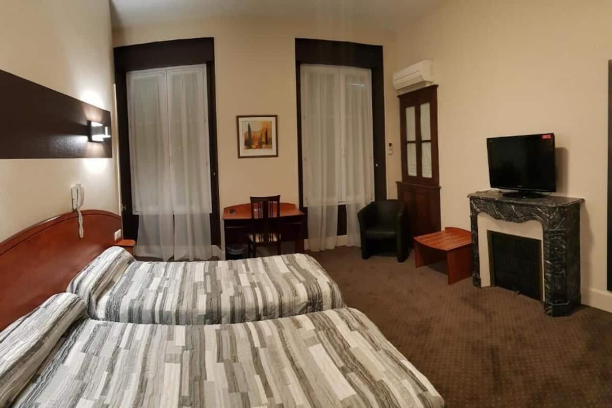 Une chambre d’hôtel équipée d’un lit, d’un bureau, d’une chaise, d’une télévision et d’une cheminée.