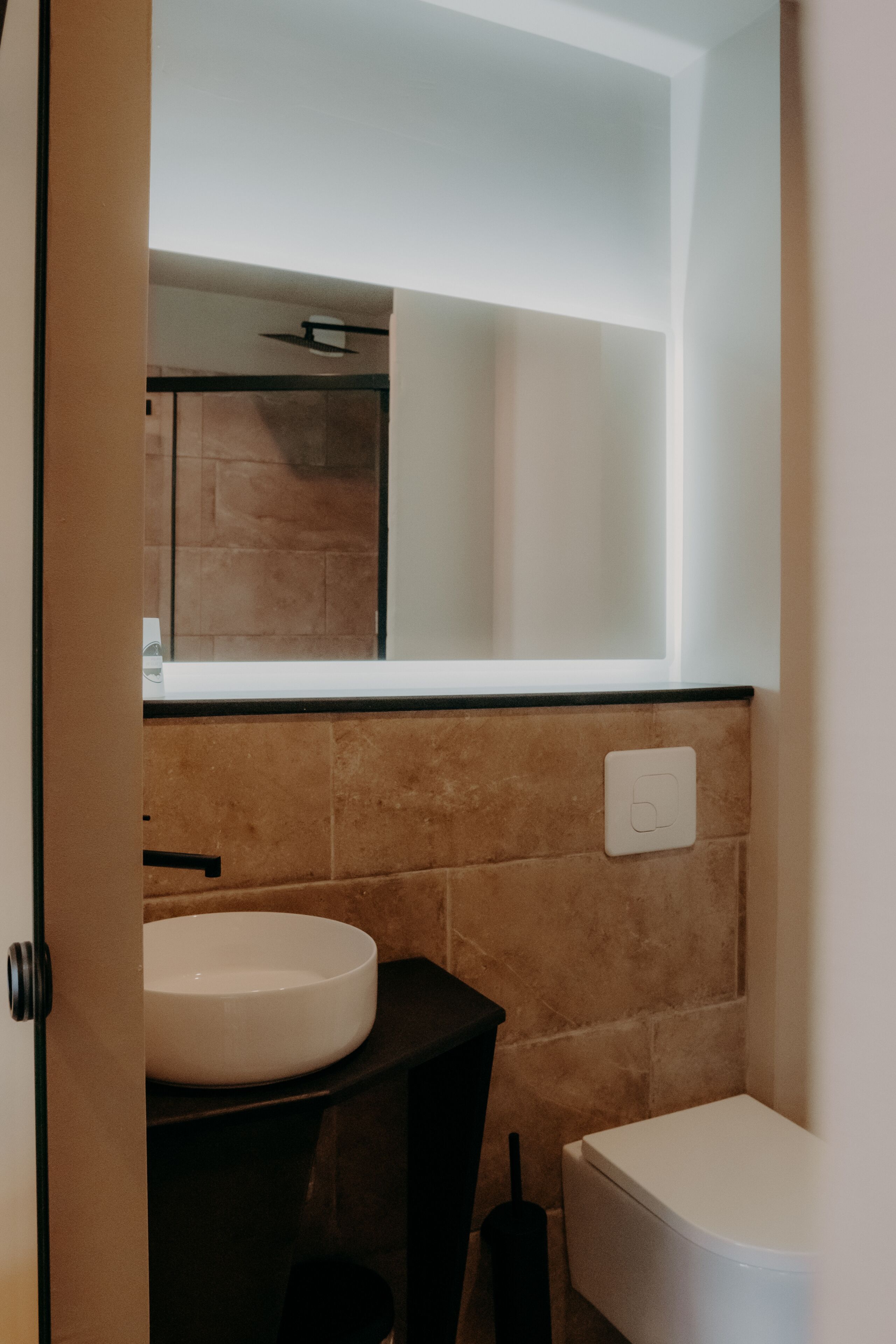 Une salle de bain avec un lavabo blanc, un meuble-lavabo noir et des toilettes blanches.