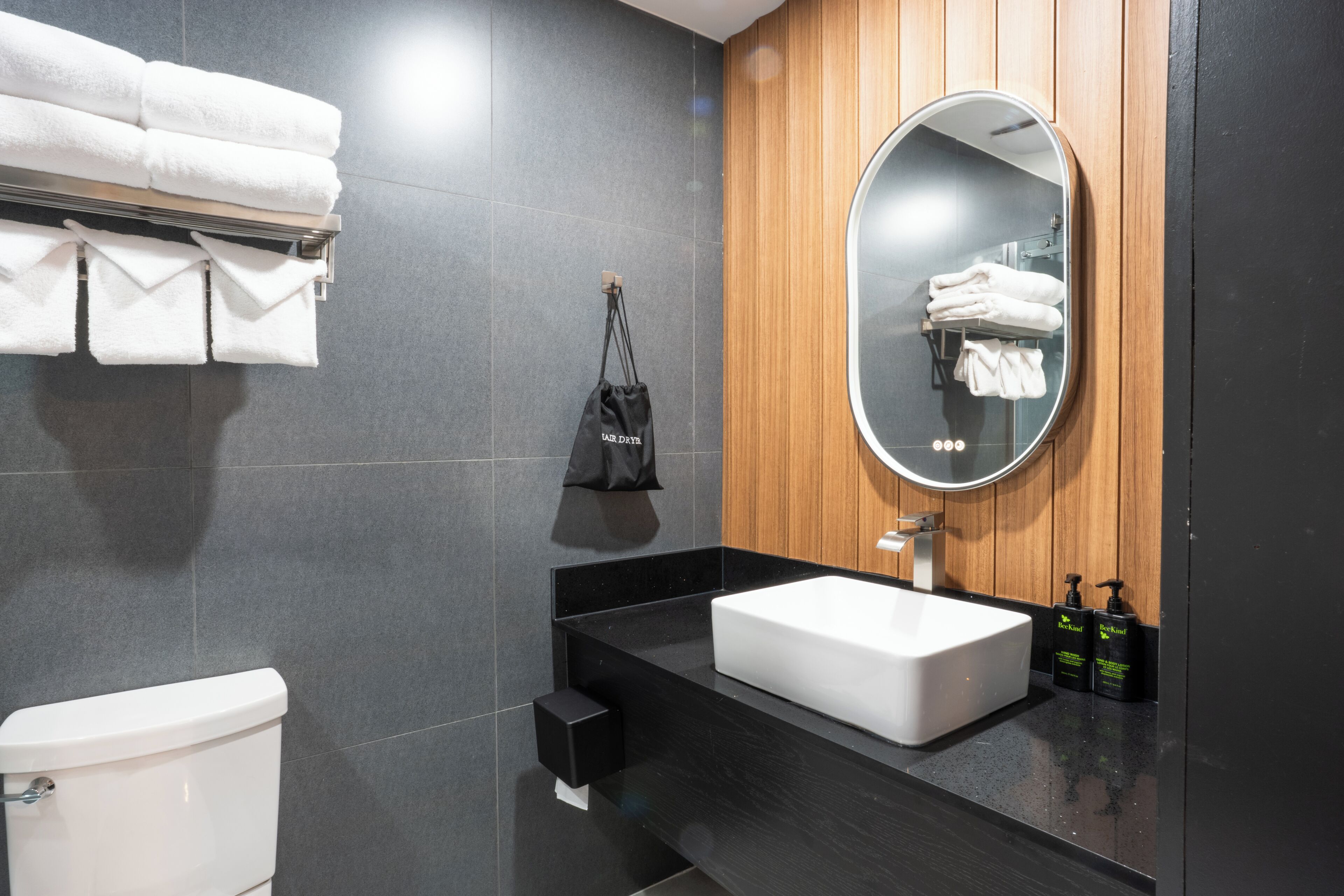 A modern bathroom with a white sink, a large mirror, and a towel rack.