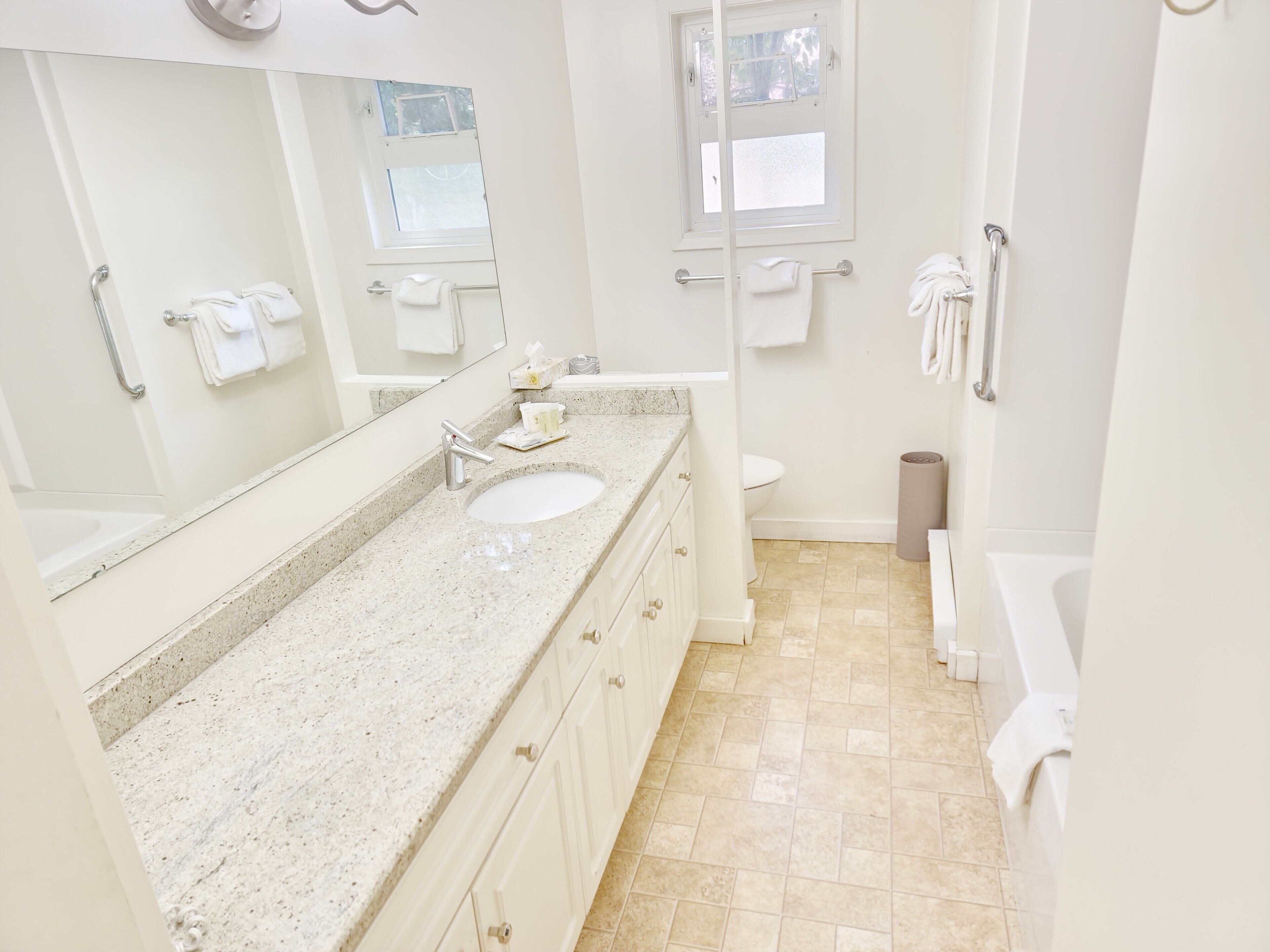 Un baño con lavamanos, espejo, inodoro y bañera.