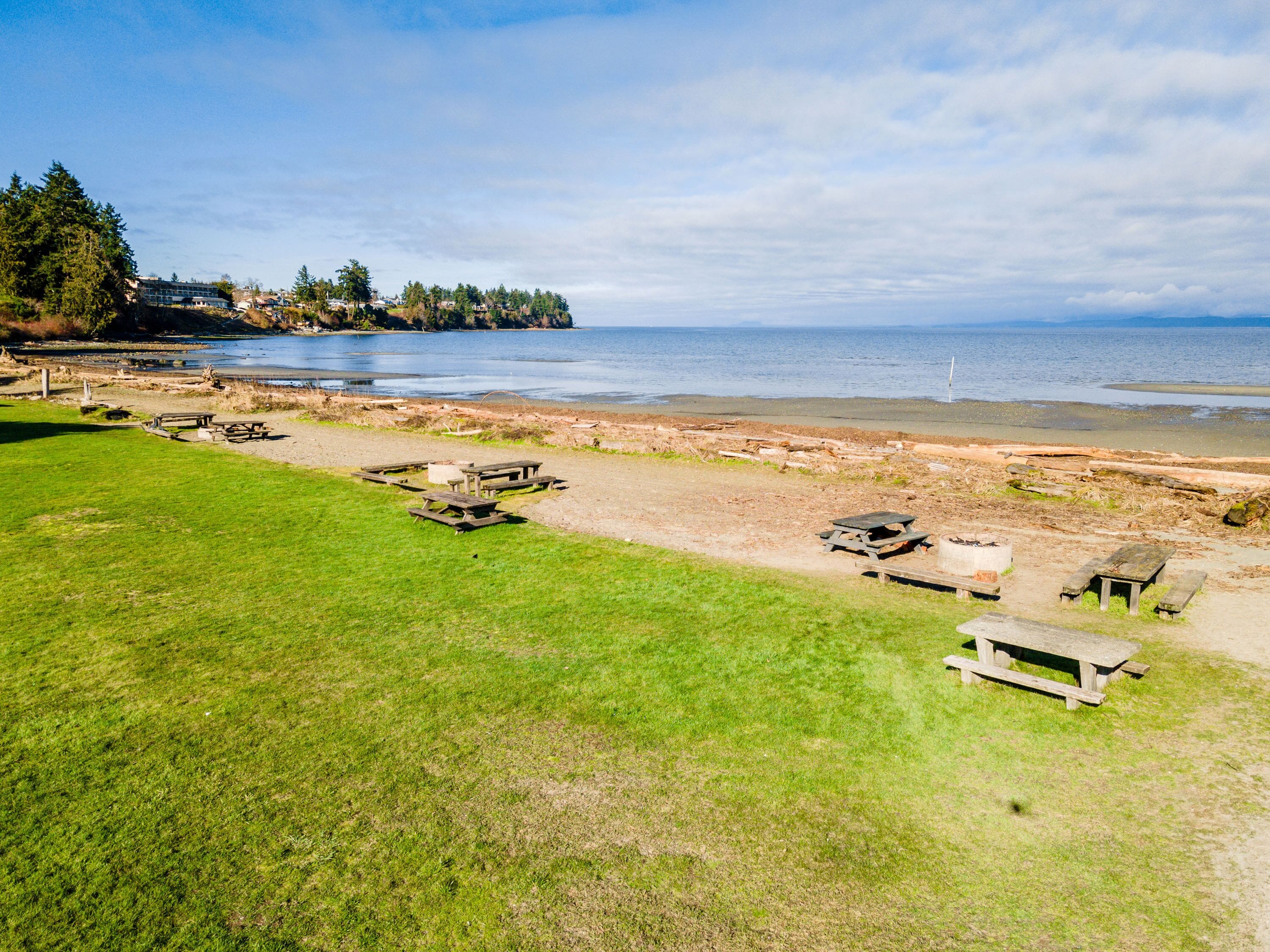 Una playa con mesas de picnic y una zona cubierta de césped.