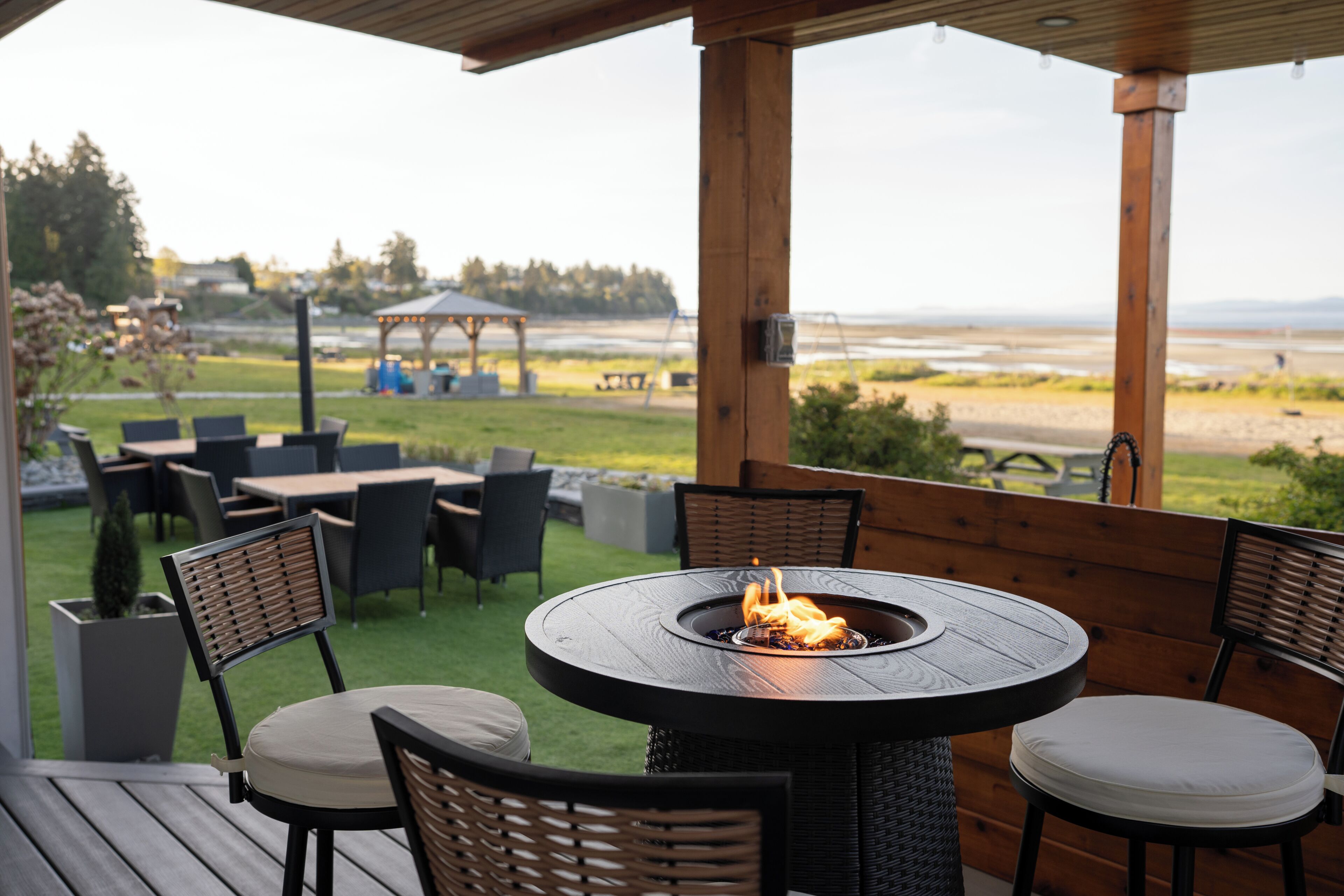 Un espace extérieur aménagé, abrité et doté d’une table ronde et de chaises, d’un foyer et d’une vue sur la plage.