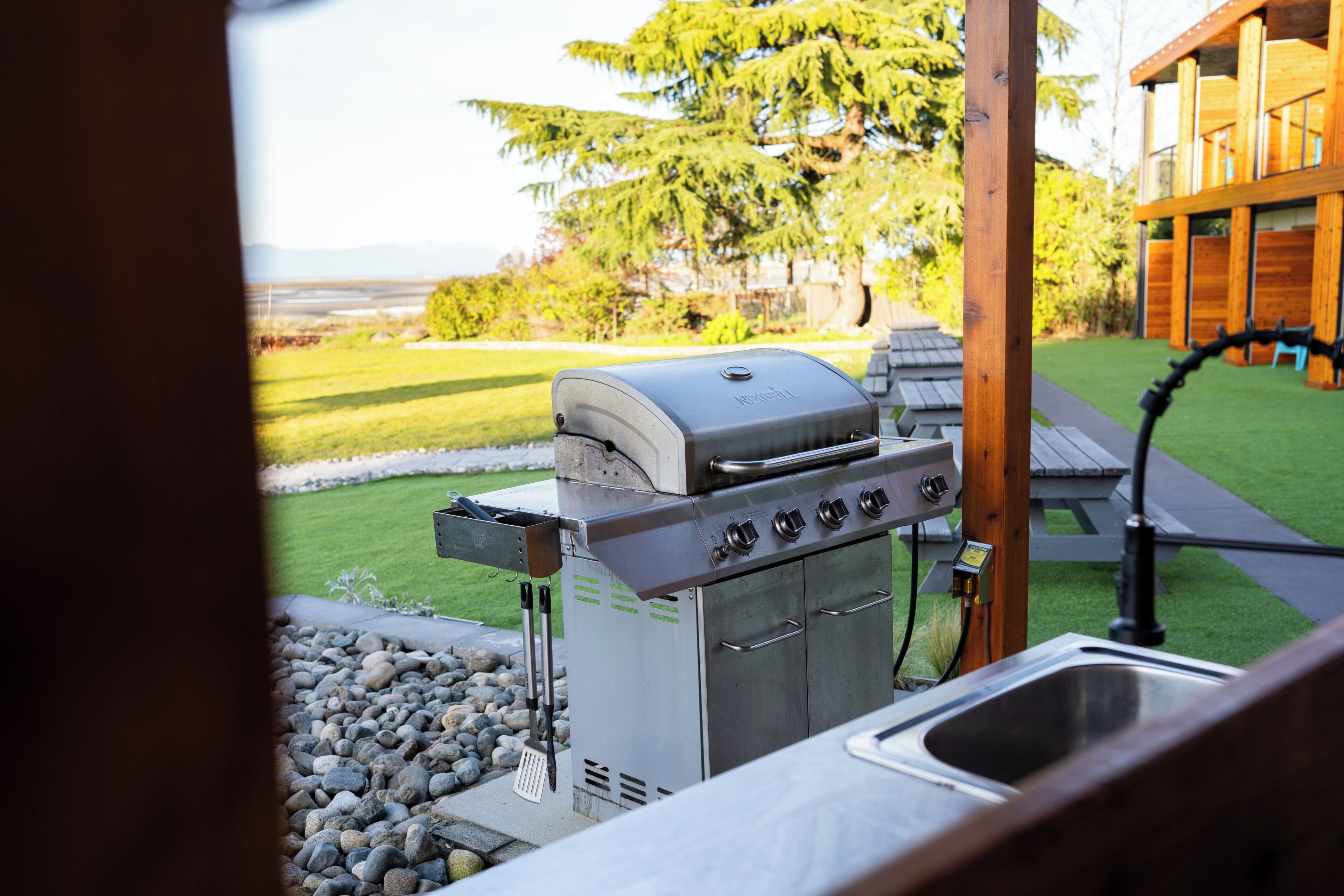 A patio with a grill, a sink, and a wooden deck.