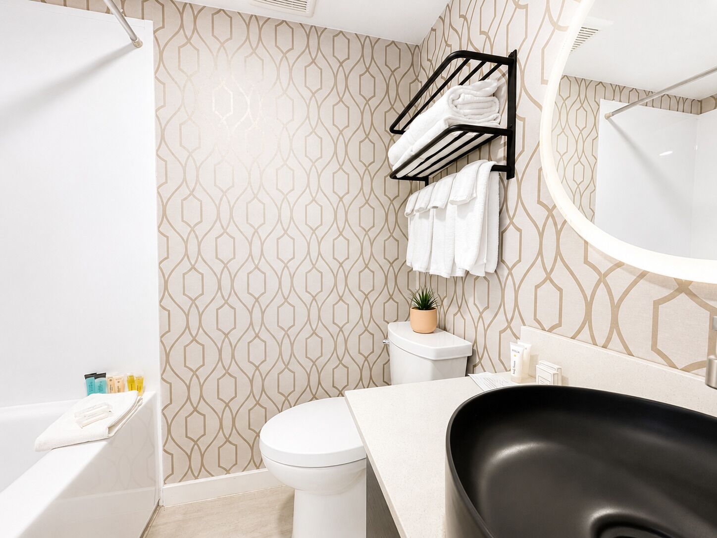 Une salle de bain moderne avec un mur à motifs, des toilettes, un lavabo et un porte-serviettes.