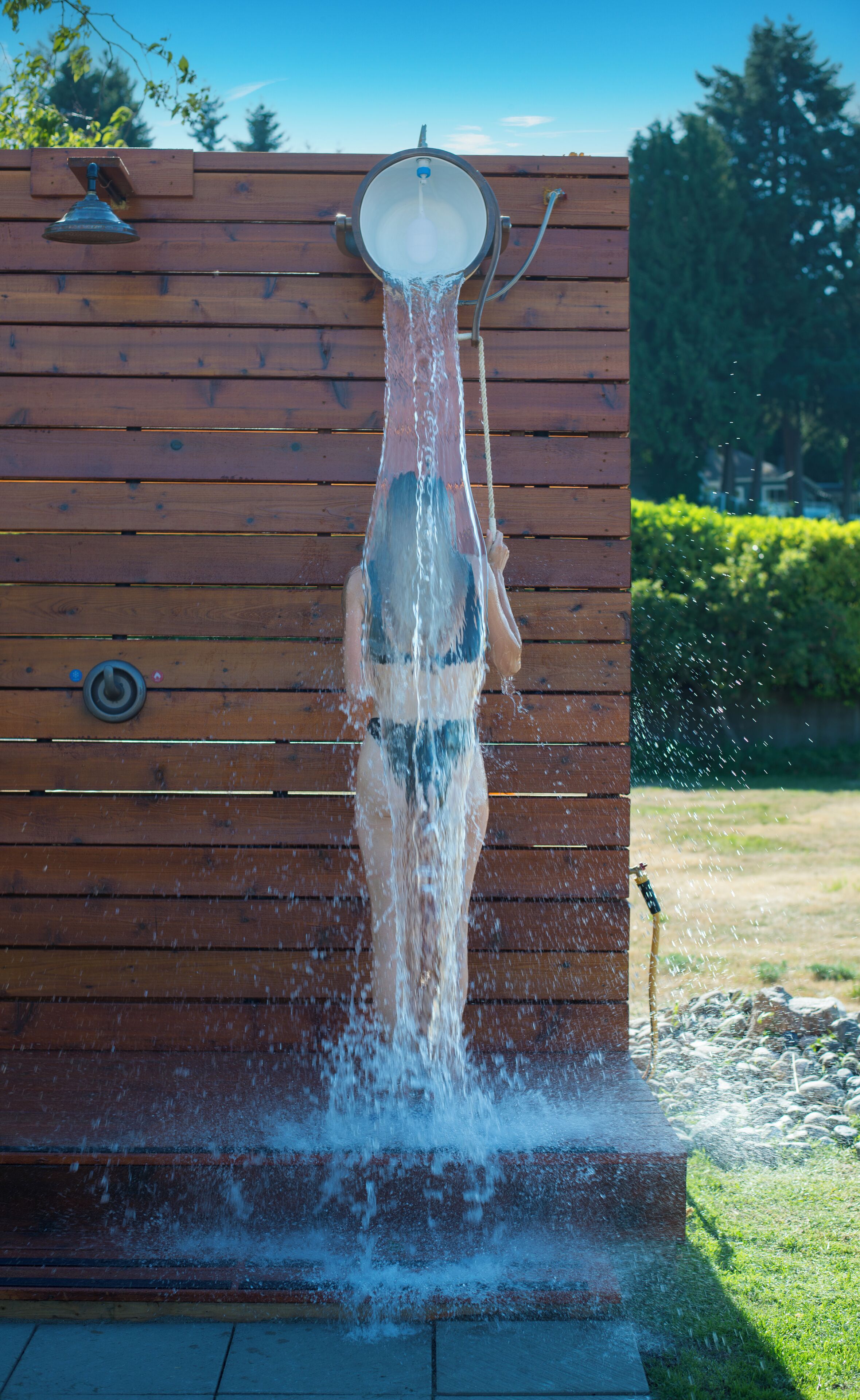 A wooden structure with a water feature, including a shower and a hose.