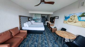 Une chambre d’hôtel avec un grand lit, un canapé, un bureau, une chaise et un ventilateur de plafond.
