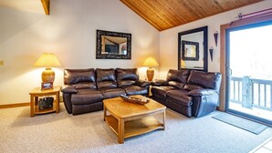 Un salon avec un plafond en bois, deux canapés en cuir, une table basse en bois et deux lampes.