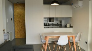 Eine moderne Küche mit weißen Schränken, einem Holzesstisch und weißen Stühlen.
