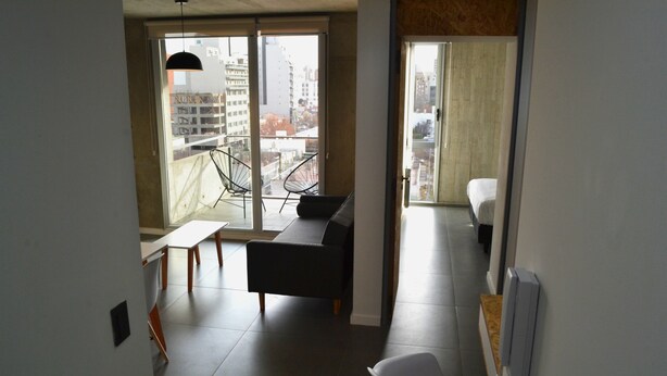 Eine moderne Wohnung mit Balkon, einem Sofa, einem Esstisch und einem weißen Stuhl.
