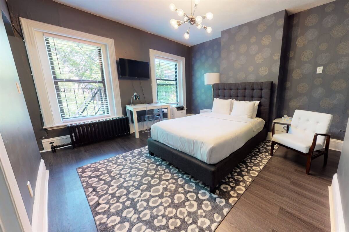 A modern bedroom with a large bed, a desk, and a chair.
