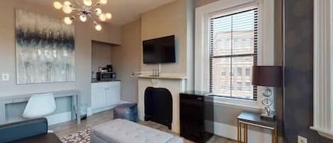 A modern living room with a sofa, ottoman, and a ceiling light fixture.