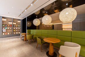A modern interior with green seating, wooden tables, and pendant lighting. - Ji Hotel (Lanzhou)