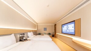 A hotel room with two beds, a TV, a desk, and a small seating area. - Ji Hotel (Lanzhou)