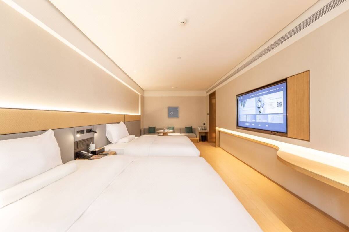 Une chambre d’hôtel avec deux lits, une télévision, un bureau et un petit coin salon.
