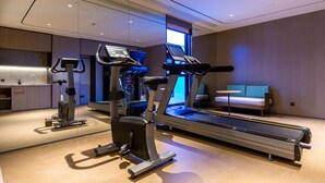 A modern hotel gym with cardio equipment, a treadmill, and a small seating area with a sofa. - Ji Hotel (Lanzhou)