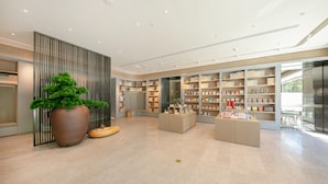 A modern interior with a large potted plant, a reception desk, and bookshelves. - JI Hotel (Beijing)