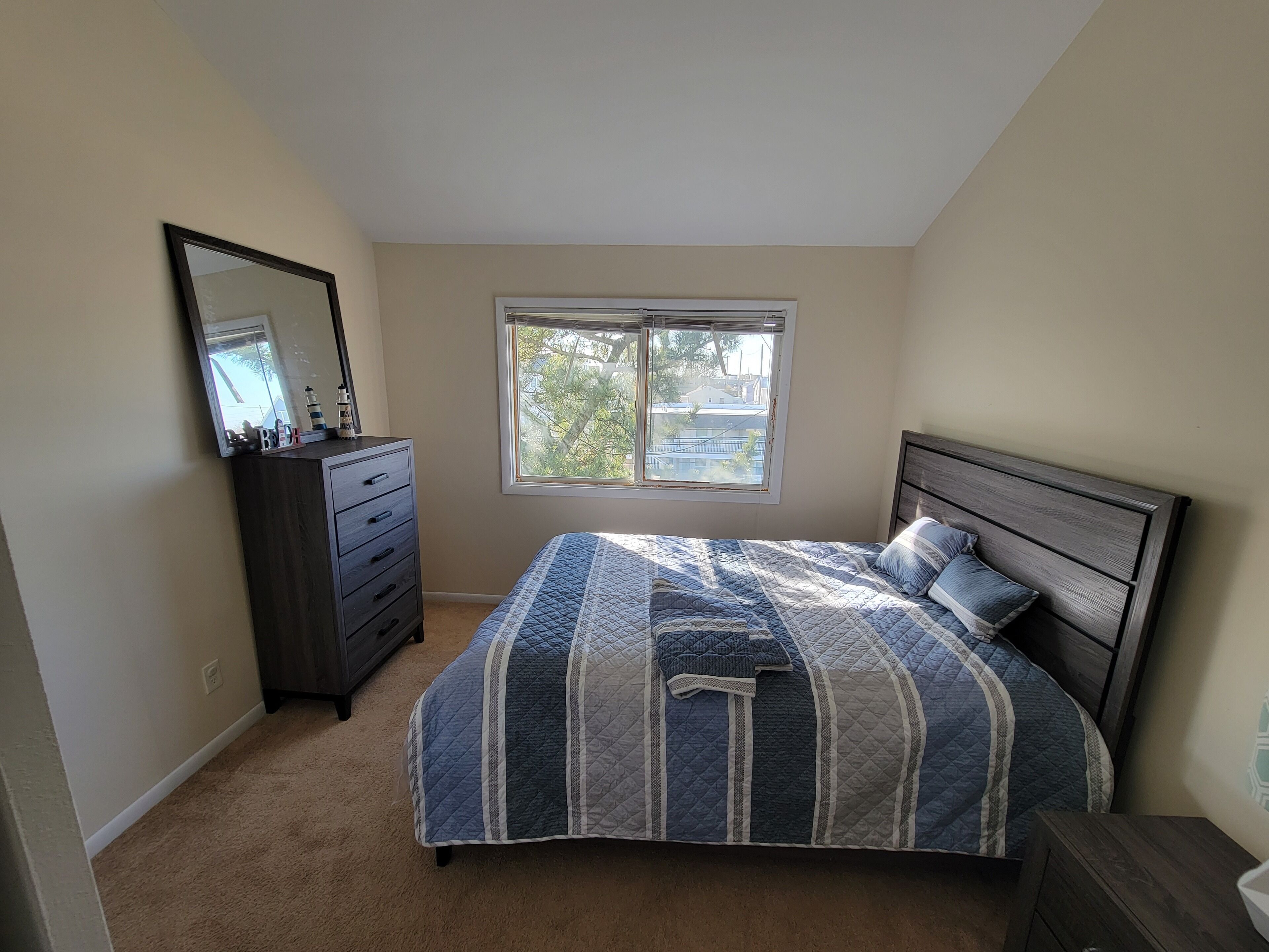 A bedroom with a bed, dresser, and a window.