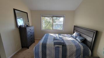 A bedroom with a bed, dresser, and a window.