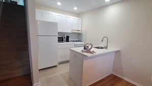 A modern kitchen with white cabinets, a built-in oven, and a sink. - Dunes Of Ortley (Seaside Heights)