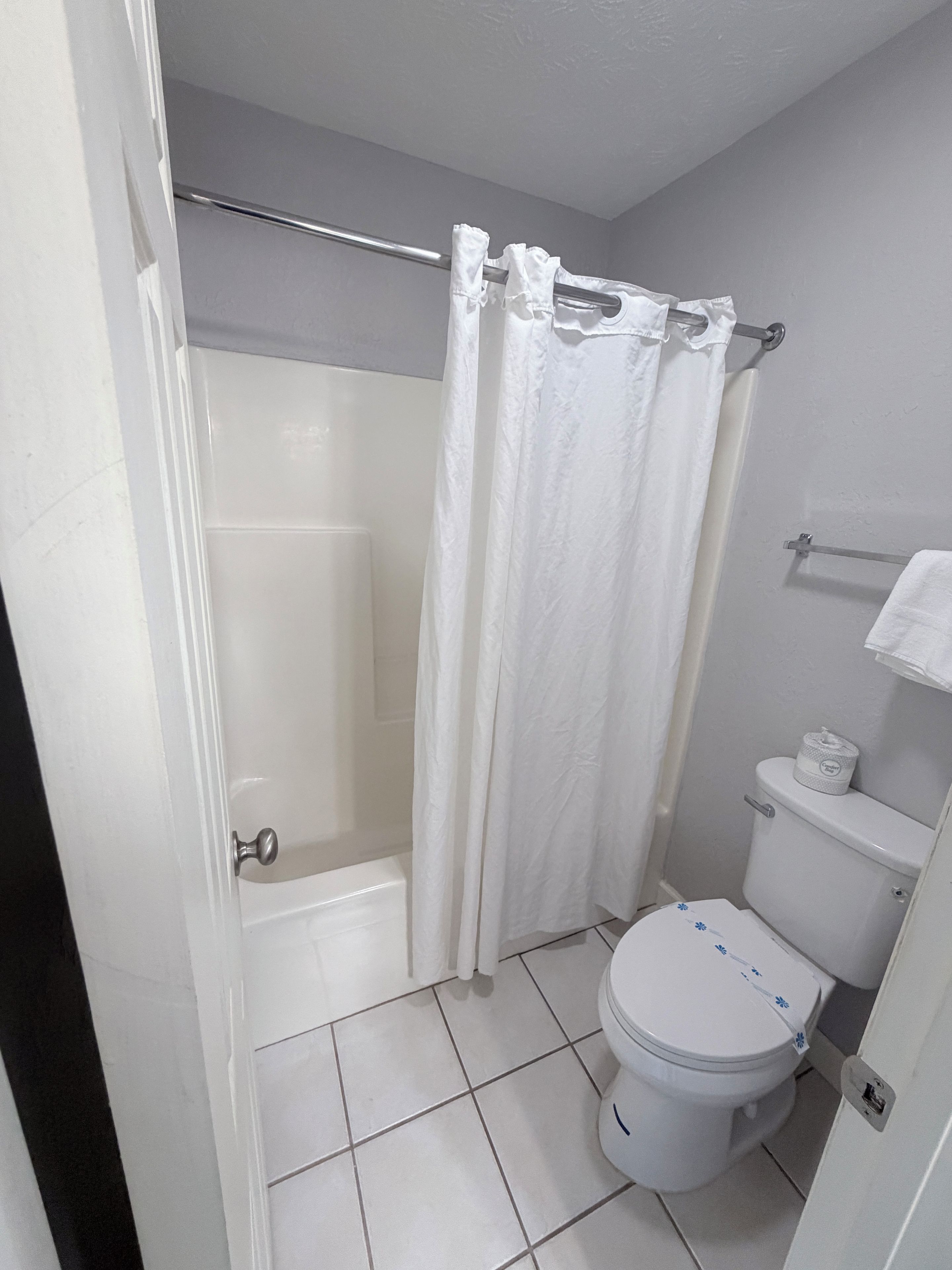 A bathroom with a shower, toilet, and a towel rack.