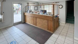 A reception area with a wooden counter, a clock, and a tiled floor. - Mountain Aire Inn Sevierville/Pigeon Forge (Sevierville)