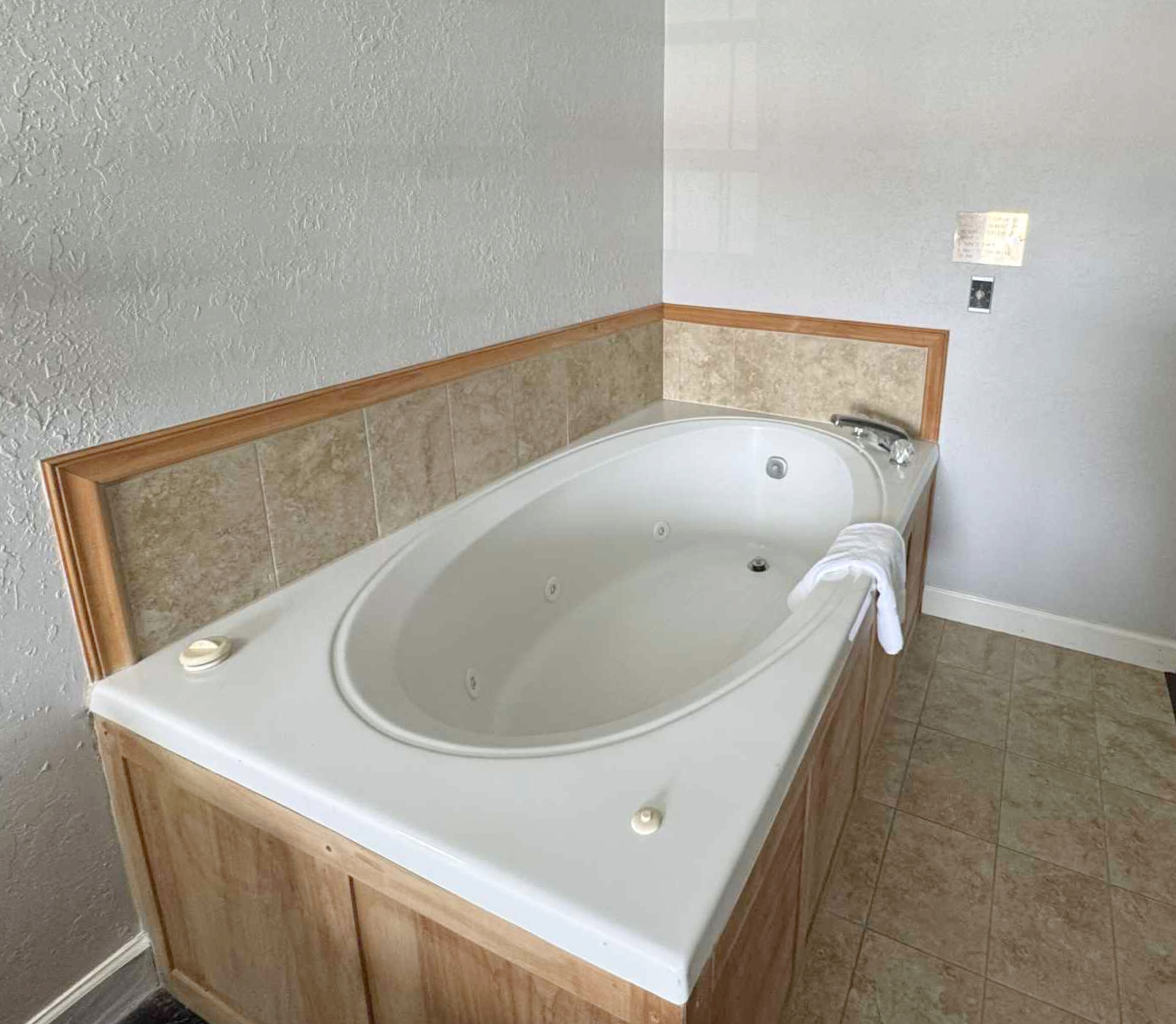 Un bagno moderno con una vasca freestanding, mobili in legno e pavimento piastrellato.
