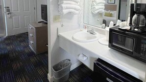 A hotel bathroom with a white sink, a mirror, a hairdryer, and a coffee maker. - Mountain Aire Inn Sevierville/Pigeon Forge (Sevierville)