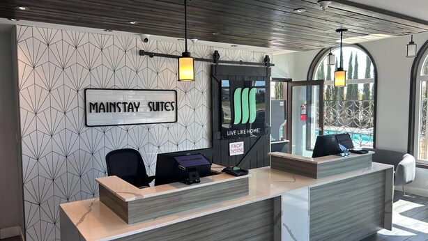 A reception desk with a sign reading "MAINSTAY SUITES" and "LIVE LIKE HOME". - MainStay Suites Moreno Valley Near March Air Reserve Base (Moreno Valley)