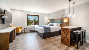 A modern hotel room with a bed, a desk, a chair, and a small table. - MainStay Suites Moreno Valley Near March Air Reserve Base (Moreno Valley)
