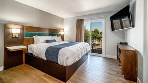 A hotel room with a large bed, bedside tables, a TV mounted on the wall, and a balcony with a view. - MainStay Suites Moreno Valley Near March Air Reserve Base (Moreno Valley)