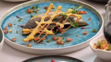 A plate with a fish, vegetables, and a decorative element.