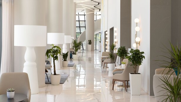 A spacious lobby with a polished floor, modern furniture, and potted plants.