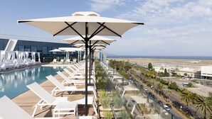 A poolside area with lounge chairs and umbrellas, overlooking a road and airport. - Sheraton Nice (Nice)