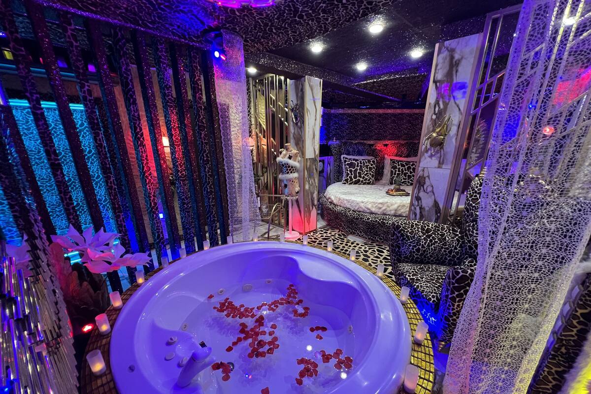 A room with a large bathtub filled with rose petals, surrounded by giraffe-patterned decor and a bed with matching pillows.
