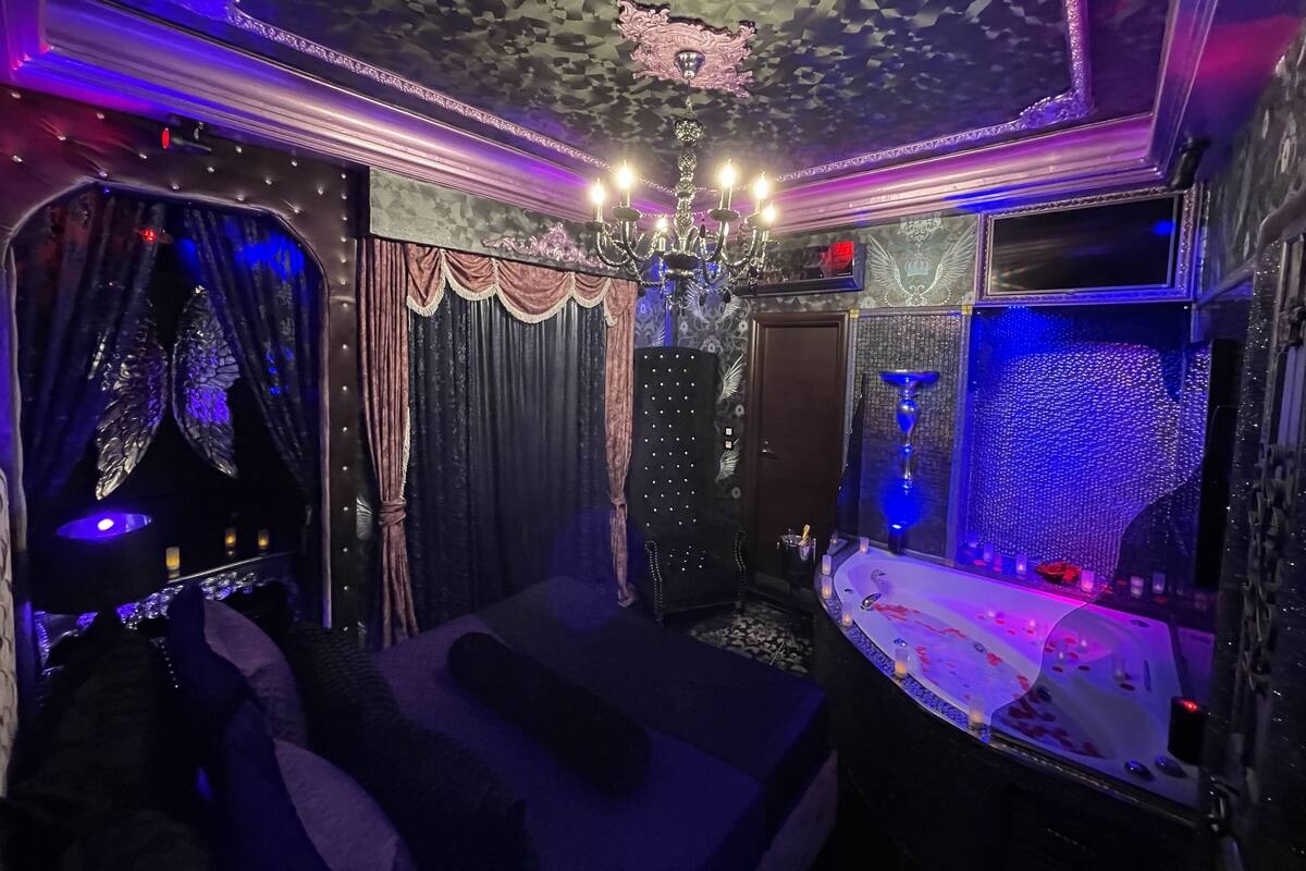 A room with a large bed, a chandelier, and a decorative ceiling.