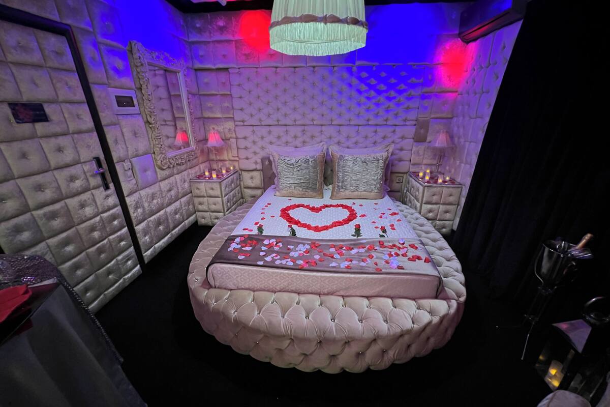 A luxurious bedroom with a tufted headboard, a heart-shaped bed decoration, and ambient lighting.