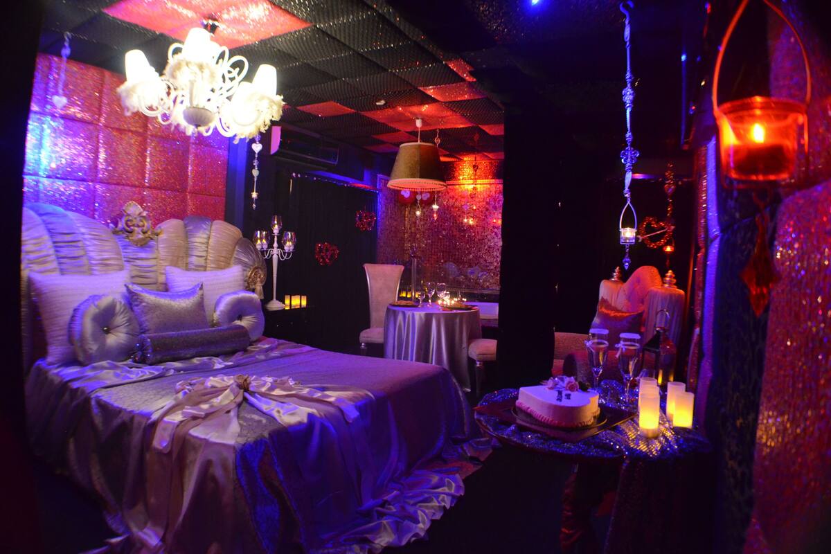 A luxurious room with a large bed, a dining table set for a meal, and a chandelier.