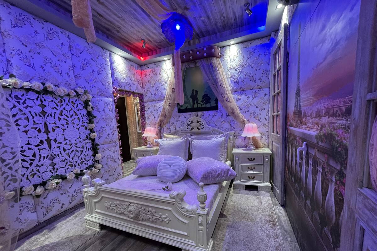 A bedroom with a large bed, two bedside tables, and a wall with a floral pattern.