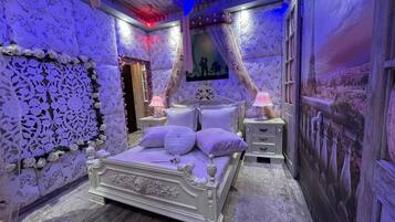 Un dormitorio con una cama grande, dos mesitas de noche y una pared con estampado floral.