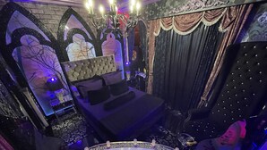 Ein luxuriöses Schlafzimmer mit einem großen Bett, einer Badewanne mit Rosenblüten und einem Chandelier.