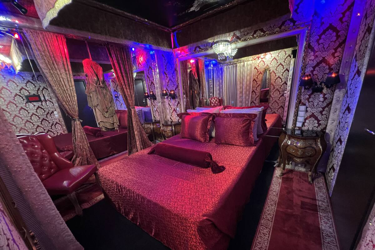 A luxurious bedroom with a large bed, ornate curtains, and a chandelier.