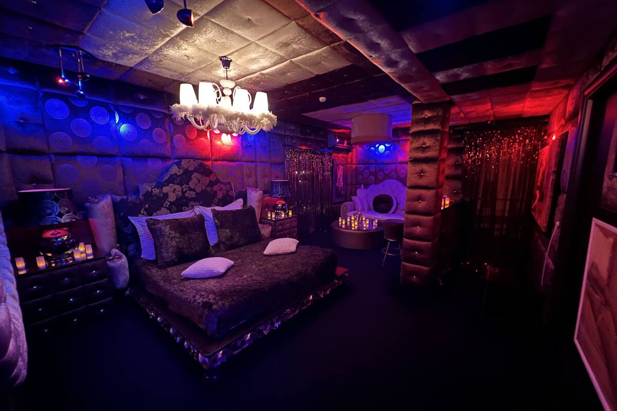 A dimly lit room with a large bed, a small table with candles, and a chandelier.
