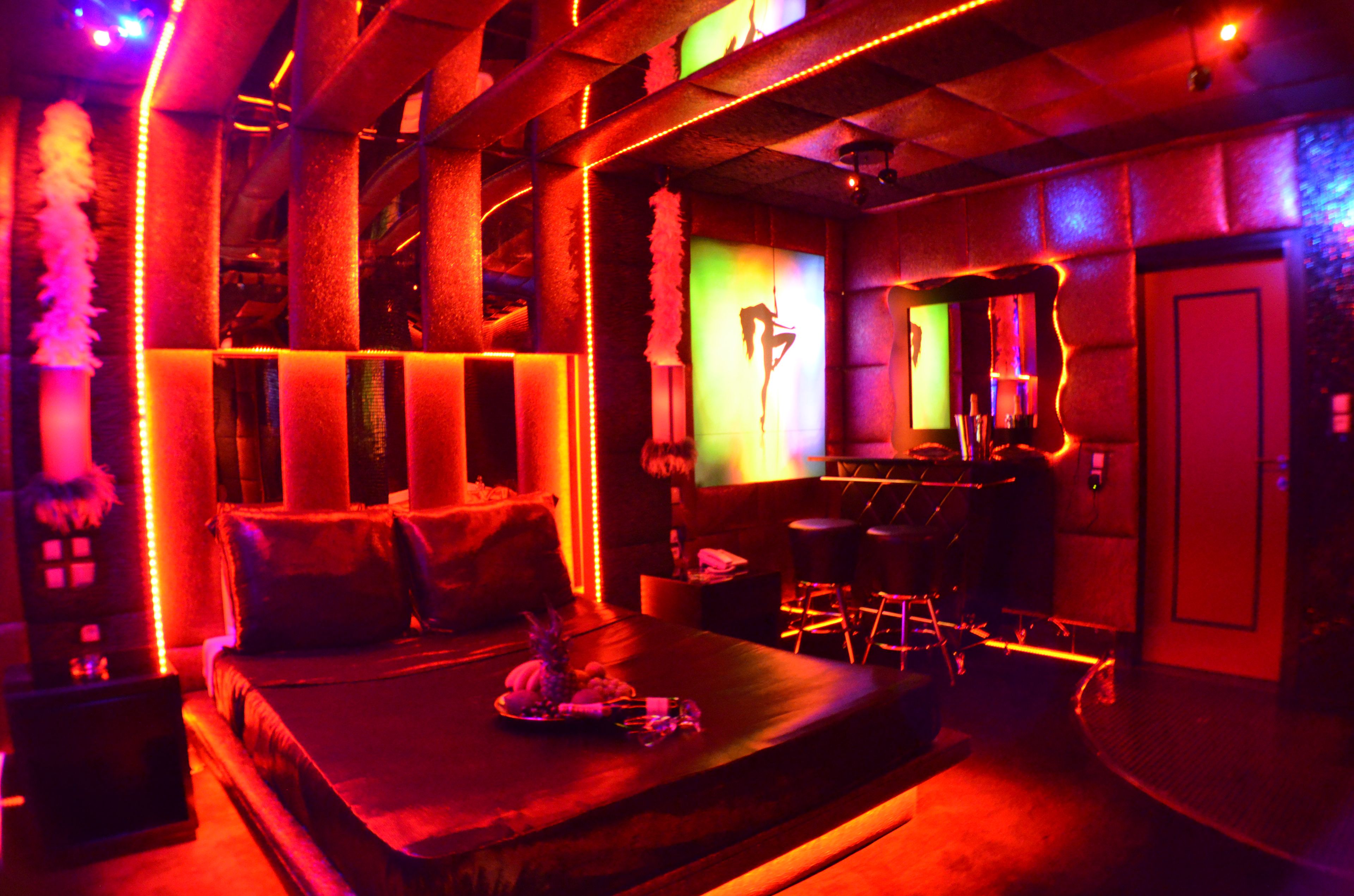Una habitación tenuemente iluminada con una cama, una zona de bar y un espejo en la pared.