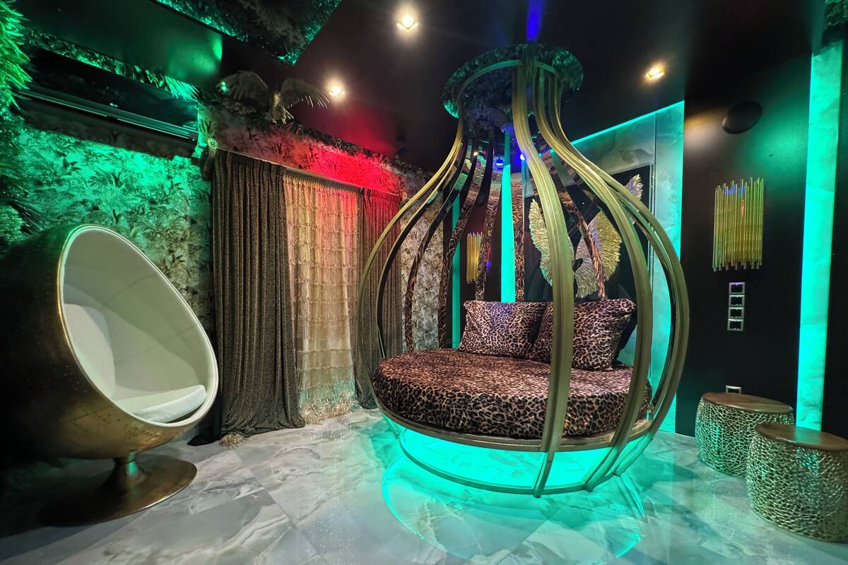 A room with a hanging chair, a round table, and a patterned sofa.