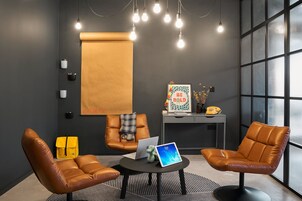 A modern office space with leather chairs, a laptop, and a tablet on a table.